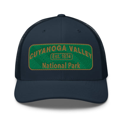 Cuyahoga National Park Hat with a green and gold embroidered national park styled patch on the front of a Yupoong 6606 navy trucker hat - front view.