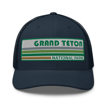 Grand Teton Hat with Retro 70's Style embroidered national park logo. Grand Teton National Park in Green on a navy Yupoong 6606 Trucker Hat front side view.