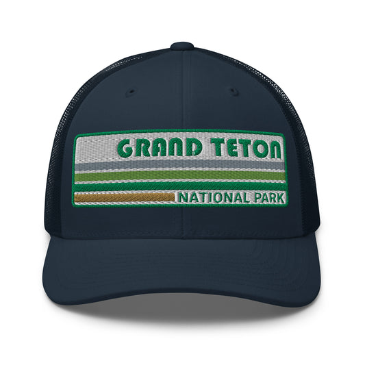 Grand Teton Hat with Retro 70's Style embroidered national park logo. Grand Teton National Park in Green on a navy Yupoong 6606 Trucker Hat front side view.